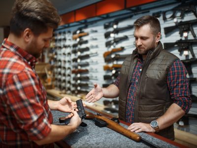 Man with owner choosing handgun in gun shop