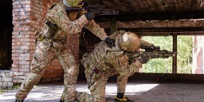 People in military uniforms with firearms are practicing combat techniques at military exercises